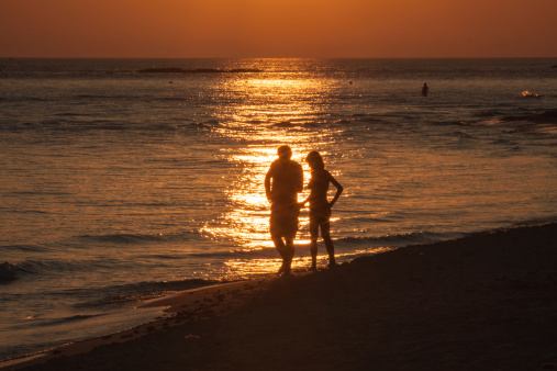 Couple walking on the seashore silouette at sunset