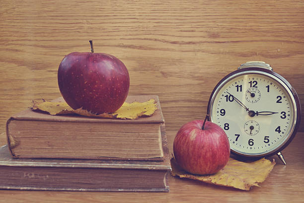 istock Old brown clock with apples and books 461243301