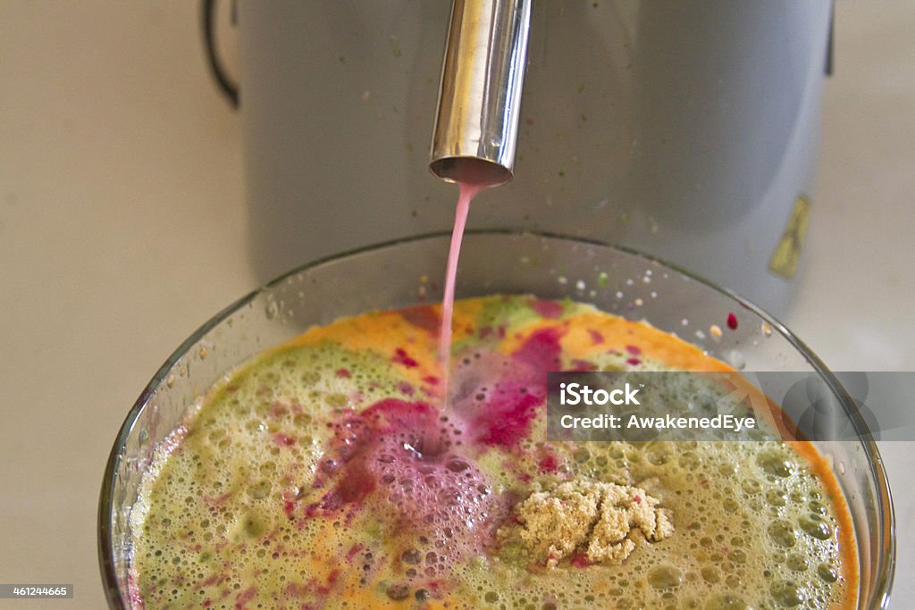 Vegetable Juicing Close up of beet juice trickling out of a juicer into a glass bowl of colorful vegetable juices and ground flax seed Alternative Medicine Stock Photo