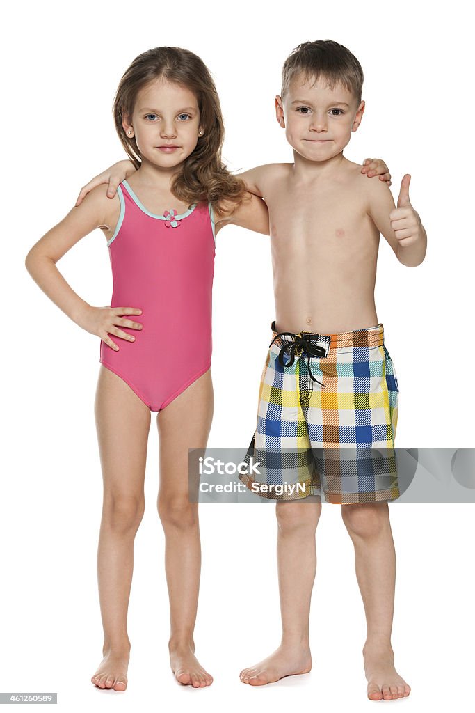 Boy giving thumbs up next to girl who are both in swimsuits A portrait of two children in swimsuits on the white background Swimwear Stock Photo