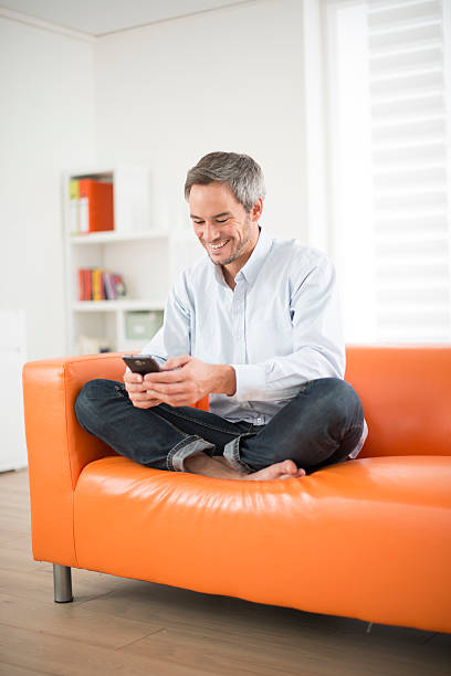 istock attractive man smiling and phone on a couch 461294145