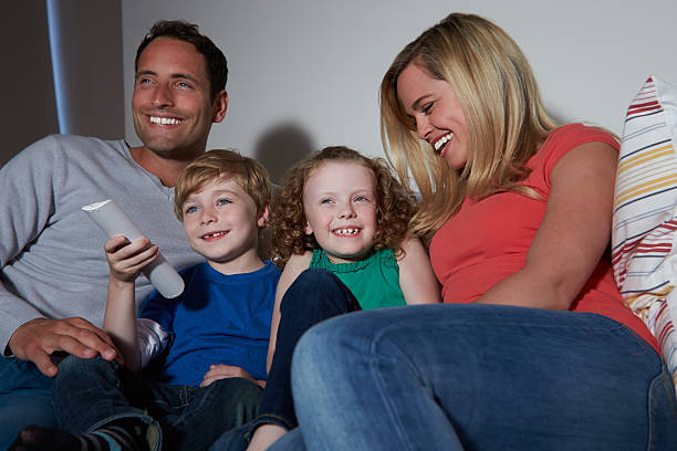 istock Family Sitting On Sofa Watching TV Together 461297343