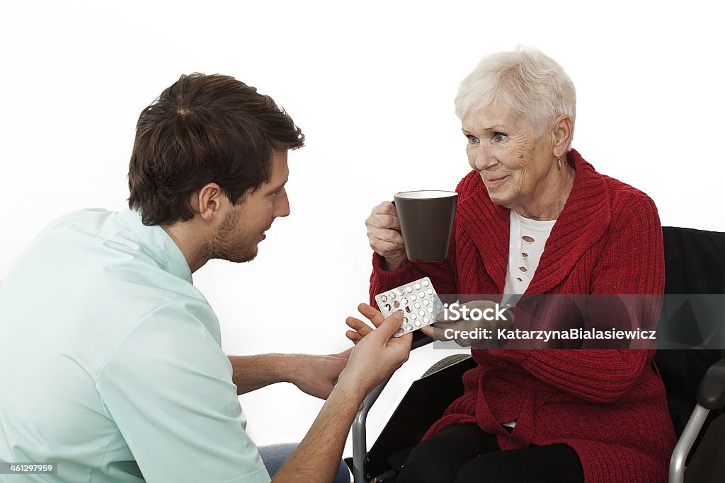 Caregiver Nurse giving medicines to elder disabled person on wheelchair 80-89 Years Stock Photo