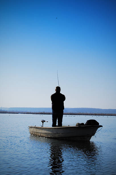 Fisherman Vs Pike Silhouette of a fisherman in pursuit for a (norther) pike. tidal inlet stock pictures, royalty-free photos & images