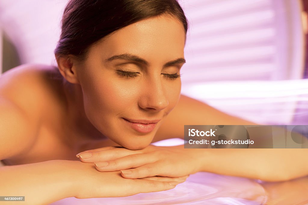 Young woman in a solarium Close-up of attractive young woman lying on tanning bed and smiling Tanning Bed Stock Photo