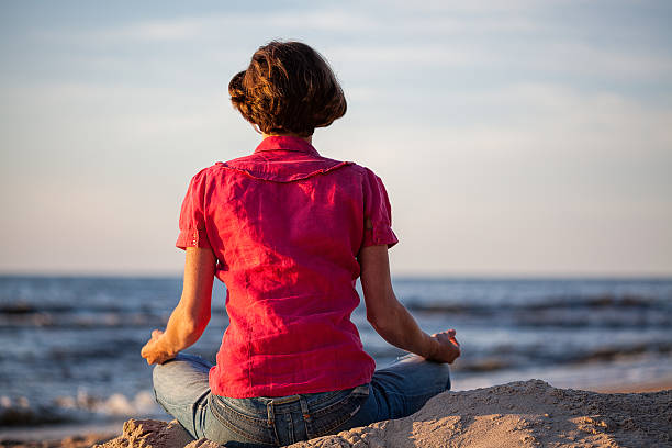 istock Woman meditating at seaside 461301939