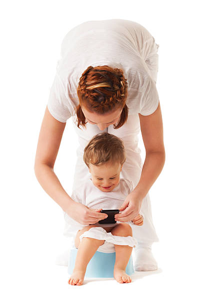 Potty training Mother performs potty training with her son using smartphone accustom stock pictures, royalty-free photos & images