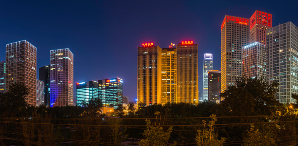 Beijing, China - 1st October 2013: Modern office buildings and futuristic skyscrapers in crowded city blocks illuminated against the blue starry skies of downtown Beijing, China. Composite panoramic image created from seven contemporaneous sequential photographs.