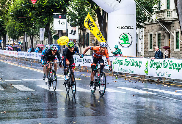 Giving a helping hand at the UCI Road World Championships Firenze, Italy - September 29, 2013: UCI World Championships road cycling - Road Race Men Elite.  The most important and last event of the competition. Four cyclists under heavy rain on Viale dei Mille in Florence. One of them  is giving a helping hand to another runner . uci road world championships stock pictures, royalty-free photos & images