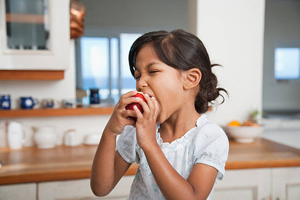 Girl in kitchen eating red apple  apple bite stock pictures, royalty-free photos & images