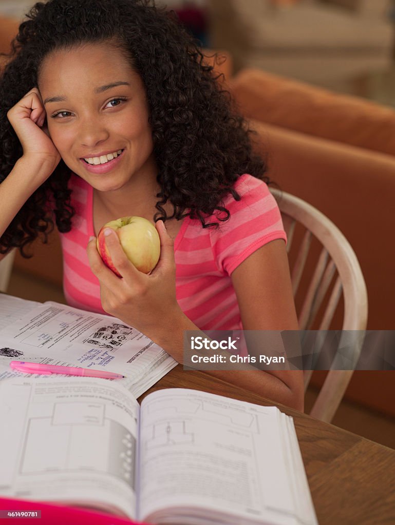 Подростковой девушка сидит за столом, есть apple Домашняя работа - Стоковые фото Подросток роялти-фри