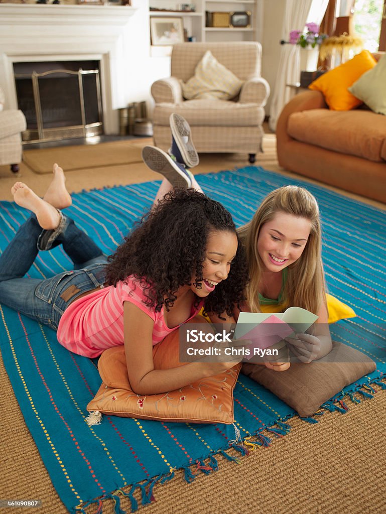 Dos chicas adolescentes acostado en el piso mirando a Nota - Foto de stock de Adolescente libre de derechos