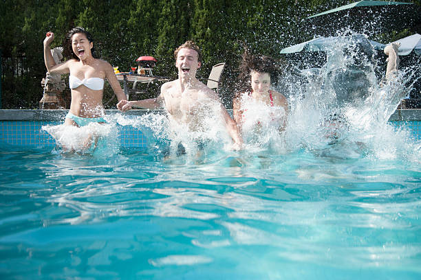 istock Four friends holding hands and jumping into a pool, mid-air 461762649