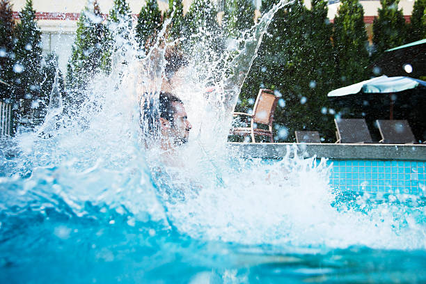 joven saltar a una piscina con salpicaduras de agua - floating on water swimming pool men water fotografías e imágenes de stock
