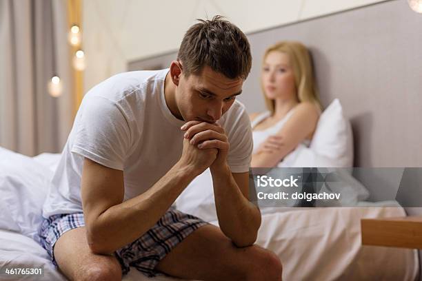 Upset Man Sitting On Bed With Disappointed Woman Stock Photo - Download Image Now - Sexual Issues, Sex and Reproduction, Problems
