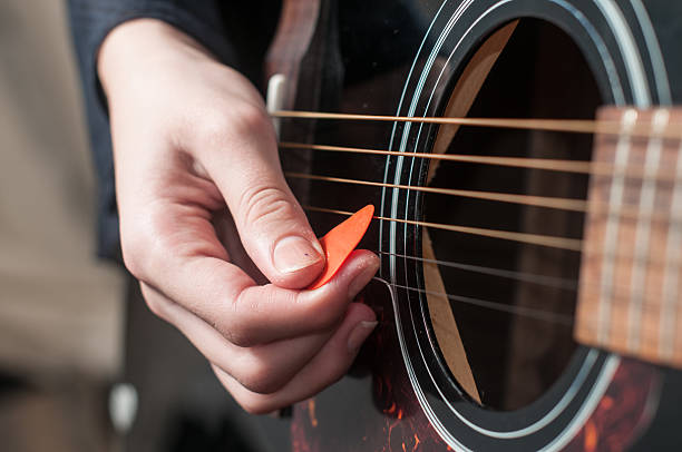 Close up of guitarist hand playing acoustic guitar Female hand playing acoustic guitar. Guitar play. Close up of guitarist hand playing acoustic guitar plectrum stock pictures, royalty-free photos & images