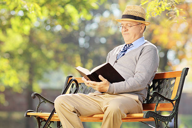 istock Senior man on bench and reading book 461794359