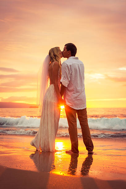 Just married couple kissing on tropical beach at sunset stock photo