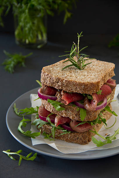 istock Grain bread sandwich with roast beef, onion and arugula. 461796411