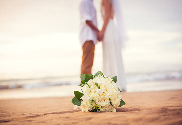 Just married couple holding hands on the beach Just married couple holding hands on the beach, Hawaii Beach Wedding bride holding bouquet stock pictures, royalty-free photos & images