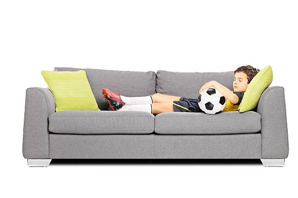 istock Boy in sportswear with a ball sleeping on modern sofa 461807863