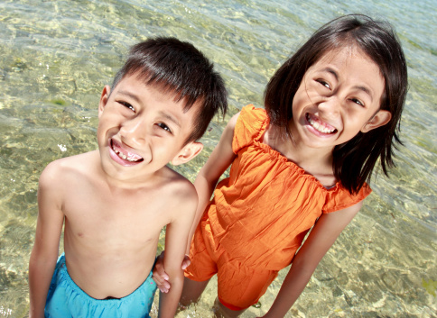 Close up portrait of happy asian kids in the beach smiling and looking at the camera