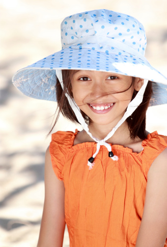 Redhead girl in warm autumn clothes in studio on dark blue background. Little girl with long hair in t-shirt and hat. Portrait