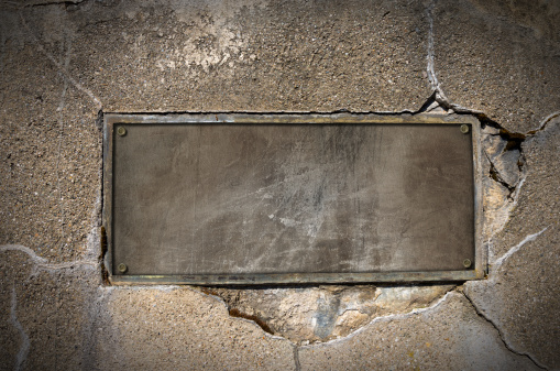 Old metal plate with bolts on cracked concrete wall