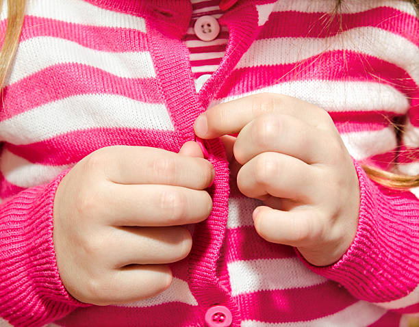 Little girl buttoning her jacket Little girl buttoning her jacket closeup buttoning stock pictures, royalty-free photos & images