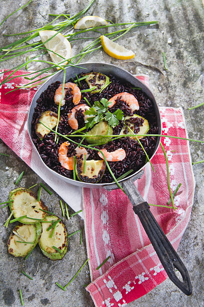 Presentation and preparation of black rice with zucchini and shrimps