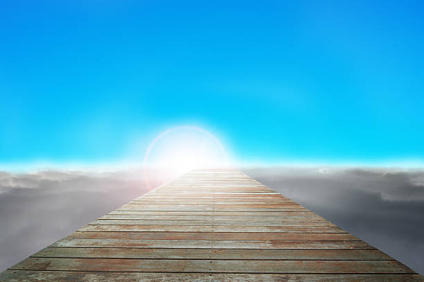 Wooden way direct to sun with cloudy below and clear blue sky
