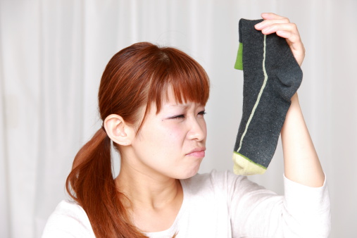 woman shrinks from a bad smell of socks.