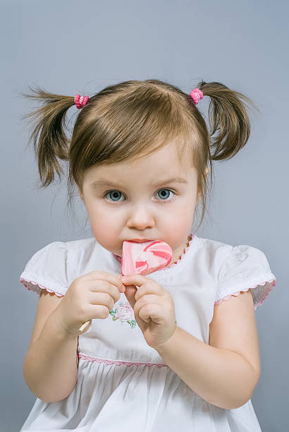 を持つ少女なハート型キャンディー - child valentines day candy eating ストックフォトと画像