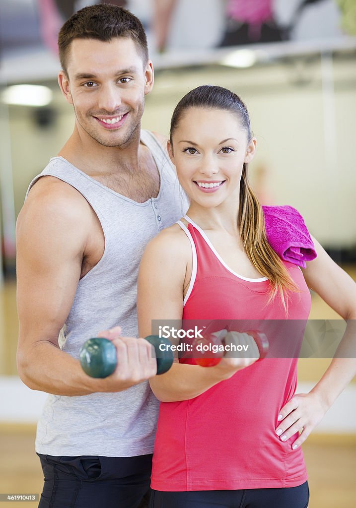 happy couple working out with dumbbells in gym fitness, sport, training, people and lifestyle concept - happy couple working out with dumbbells in gym Active Lifestyle Stock Photo