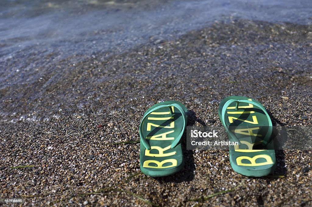 Flip flops on the beach Pair of green flip flops with "Brazil" text on it lays on a beach Beach Stock Photo