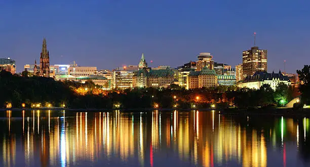 Ottawa at night over river with historical architecture.