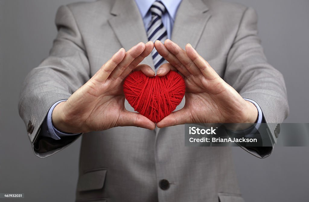 Businessmen is holding out a red heart Man holding a red woolen heart concept for valentine's day, business customer care, charity, social and corporate responsibility Social Responsibility Stock Photo