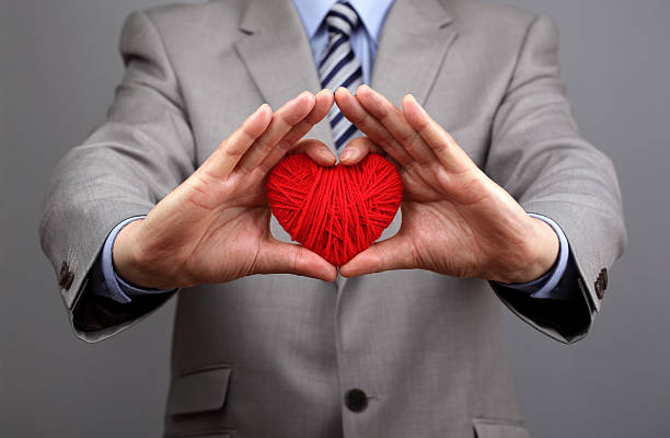 Businessmen is holding out a red heart Man holding a red woolen heart concept for valentine's day, business customer care, charity, social and corporate responsibility social responsibility photos stock pictures, royalty-free photos & images