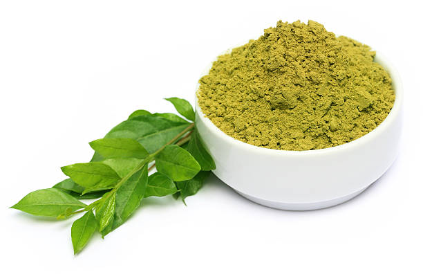 Henna leaves and powder on a white bowl