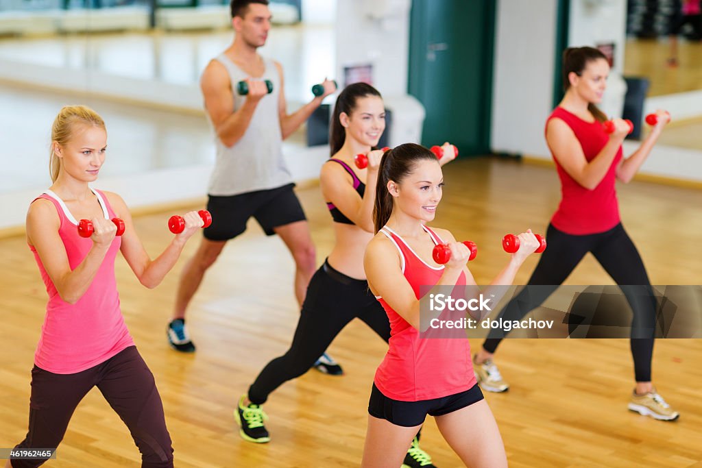 group of smiling people working out with dumbbells in gym fitness, sport, training, gym and lifestyle concept - group of smiling people working out with dumbbells in the gym Dumbbell Stock Photo