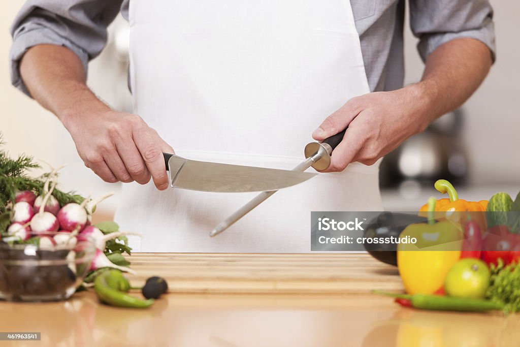 A chef sharpening a knife in his kitchen  - Royalty-free Keukenmes Stockfoto