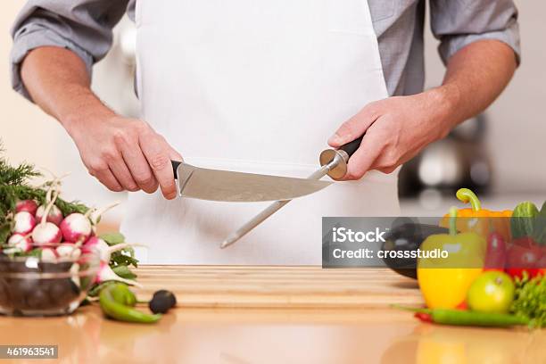 A Chef Sharpening A Knife In His Kitchen Stockfoto en meer beelden van Keukenmes - Keukenmes, Slijpen, Staal