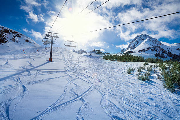 Ski lift with seats going over the mountain and paths from skies and snowboards