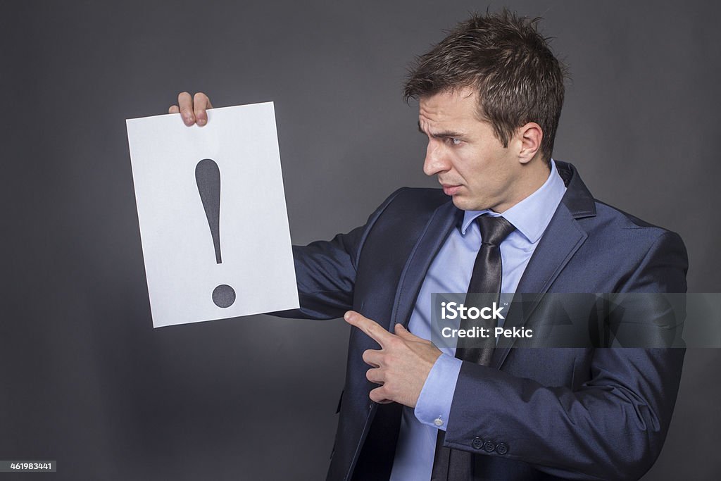 Businessman holding exclamation mark Businessman holding a sheet with exclamation mark on it A Helping Hand Stock Photo