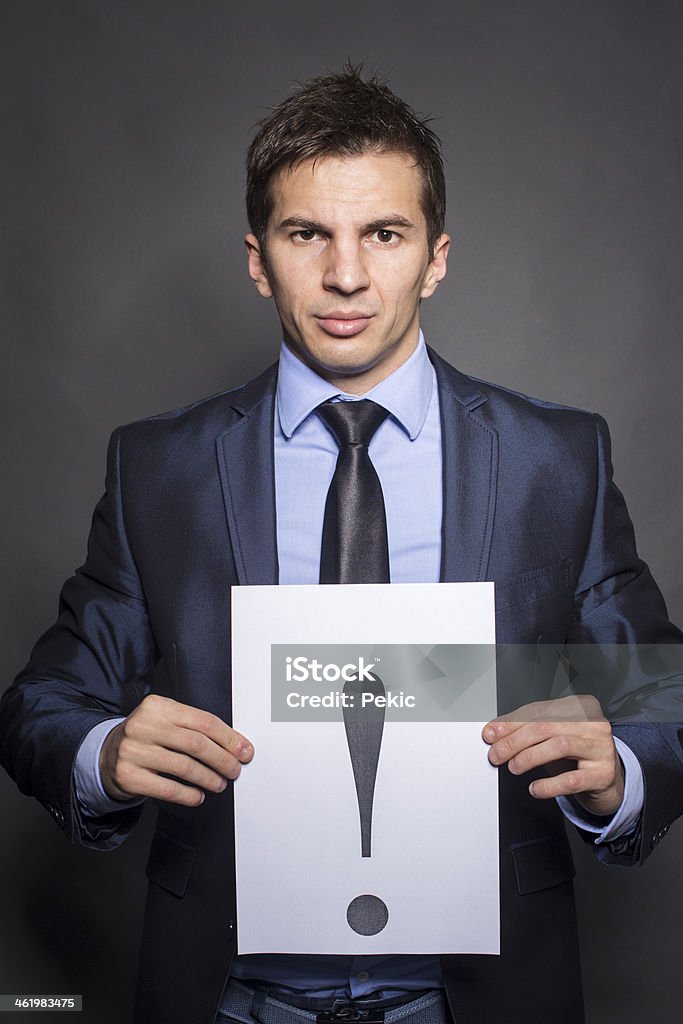 Businessman holding exclamation mark Businessman holding a sheet with exclamation mark on it A Helping Hand Stock Photo