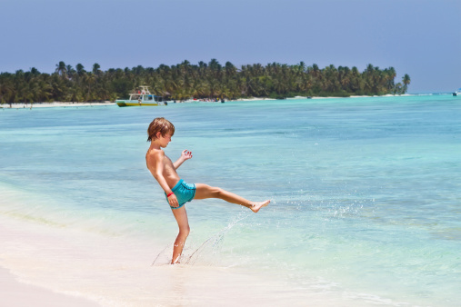 Little boy playing in the ocean on a tropical beach