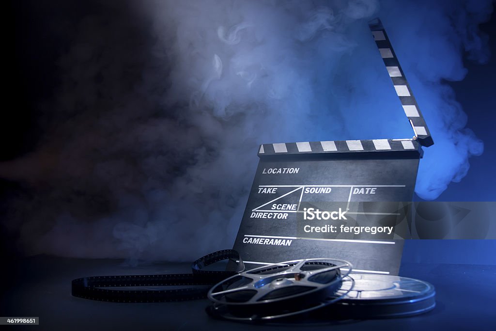 Movie clapper and film reels Filmmaking concept scene with clapper and dramatic lighting Film Slate Stock Photo