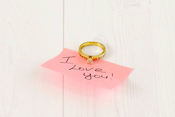 istock gold ring with pink sticker on white wood 461998833