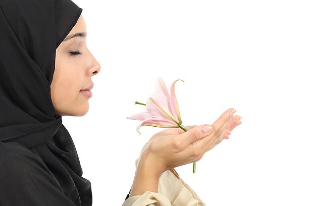 femme arabe porter un hijab sentir une fleur - aromatherapy single flower flower holding photos et images de collection