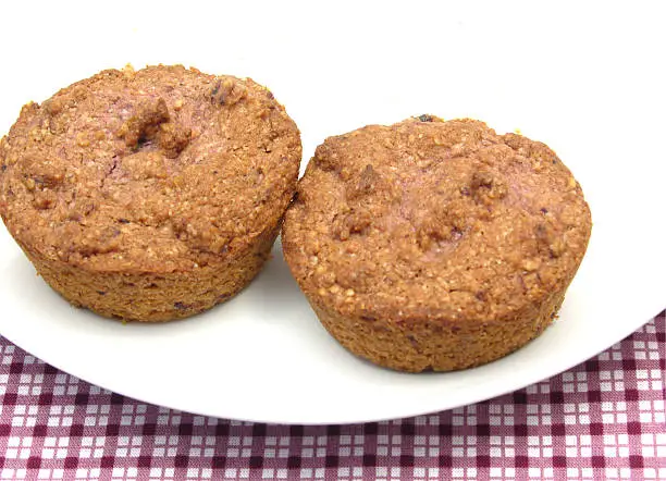 Two raspberry muffins on a white plate of chinaware